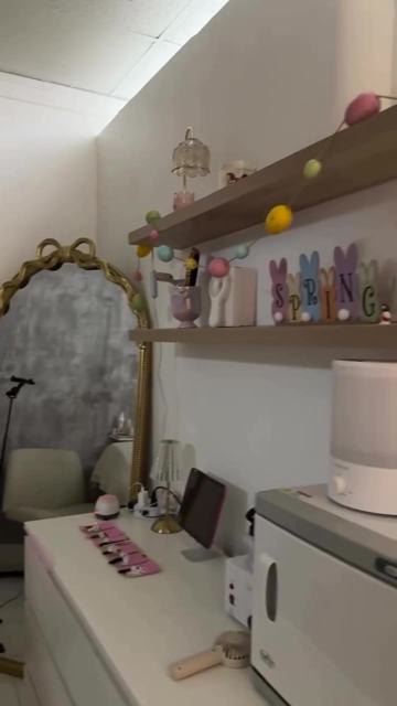 Her suite: a gold bow mirror, floating shelves and a white vanity